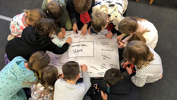 Kinder des Projektes Aktion Zivilcourage malen gemeinsam auf einem Canvas